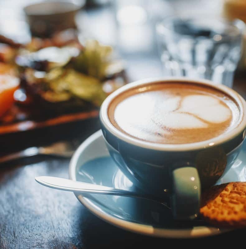A cup of milky Puerto Rican coffee served with a biscuit